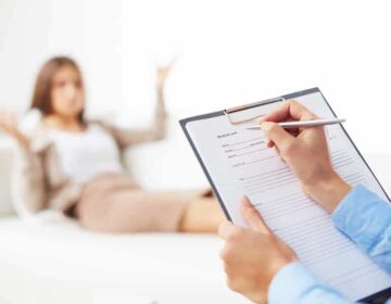 Professional psychiatrist consulting her patient and making notes in application form